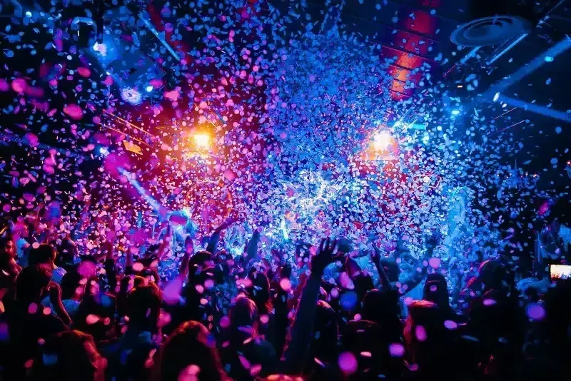 Confetti over een volle zaal met handen in de lucht tijdens een show van Knal & Co.