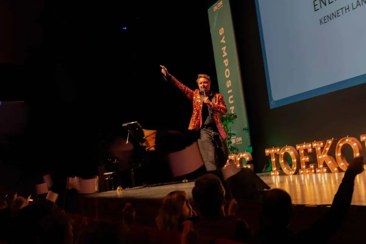 Kenneth op een congrespodium met de arm omhoog tijdens de Energizer