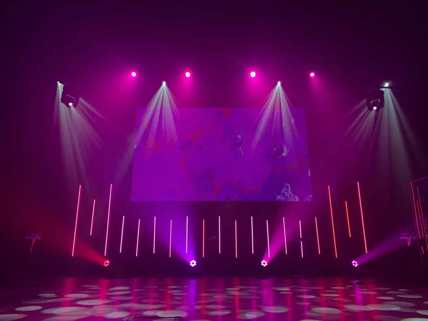 Podium met paarse spots en moving heads voor aanvang van een show